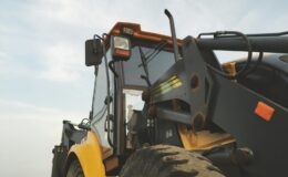 Detailed view of a yellow excavator against a clear sky at a construction site.