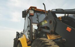 Detailed view of a yellow excavator against a clear sky at a construction site.